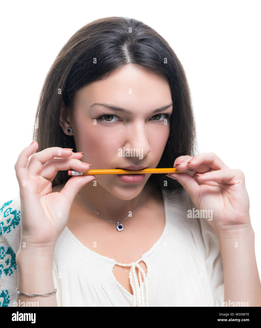 Young woman holding a pencil in her teeth on white background Stock