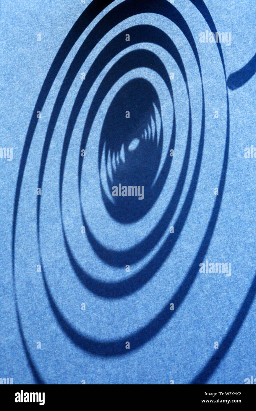Industrial concept. Closeup of shadow of spiral on blue background Stock Photo