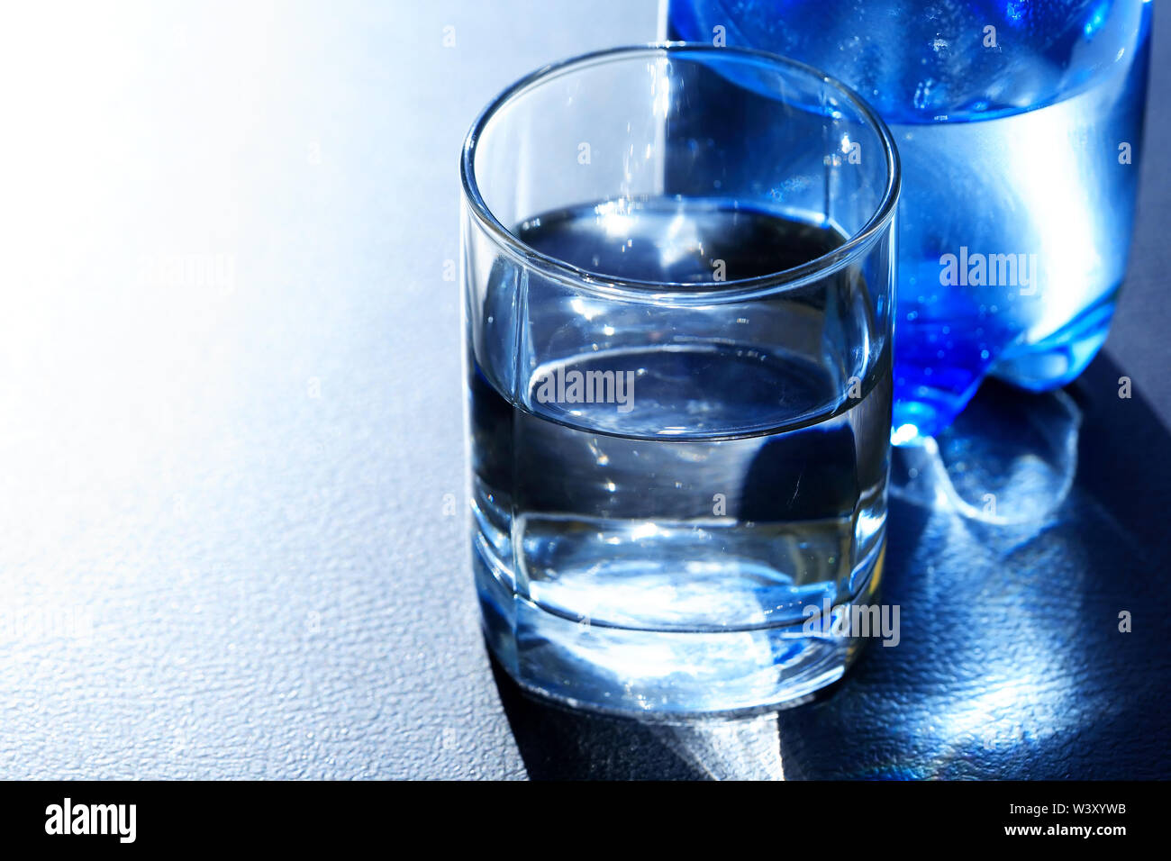 Closeup of glass of mineral water near blue plastic bottle Stock Photo