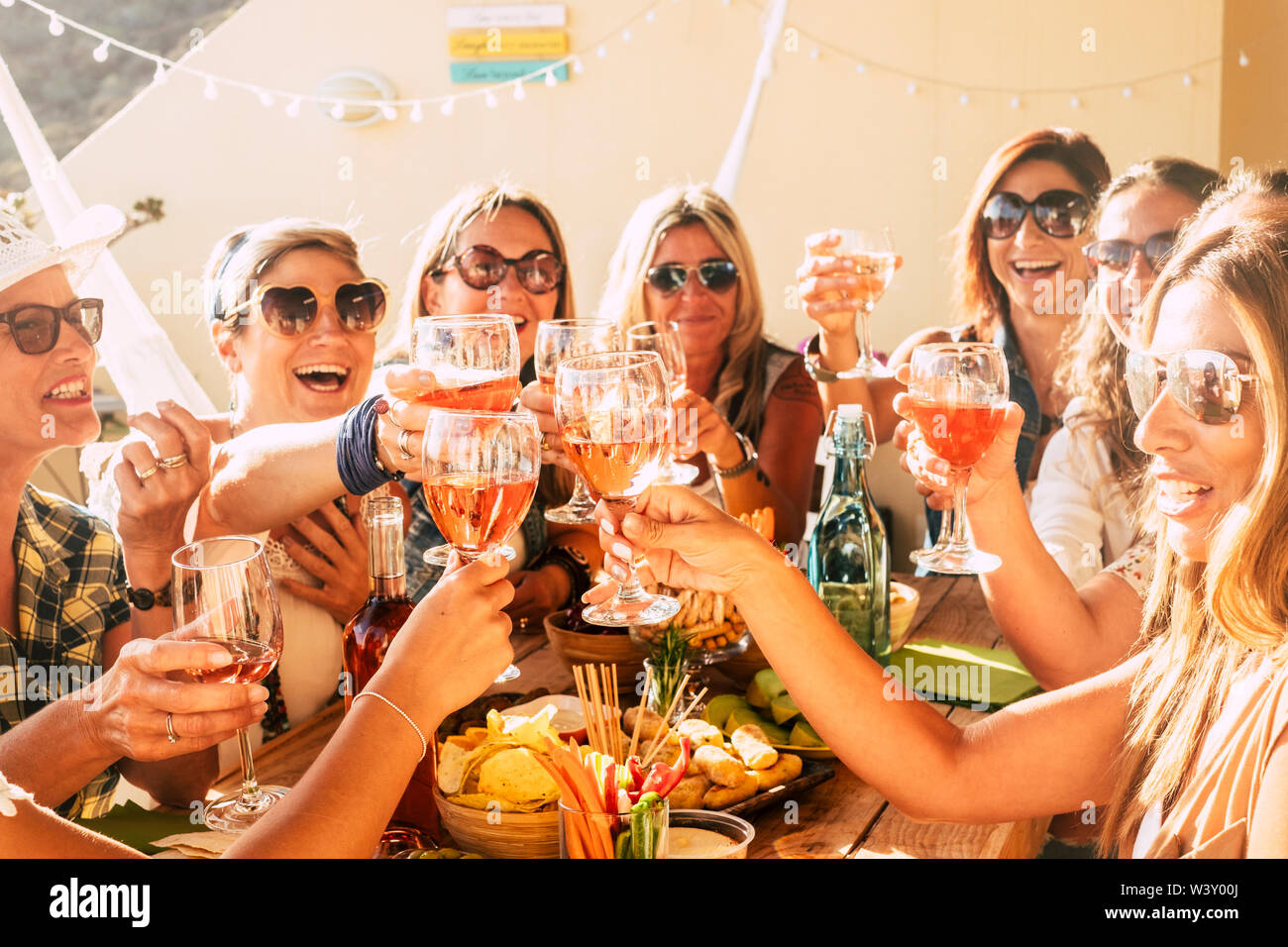 People having fun in friendship - group of cheerful happy caucasian young women laugh and smile together clinking and toasting with red wine during ce Stock Photo