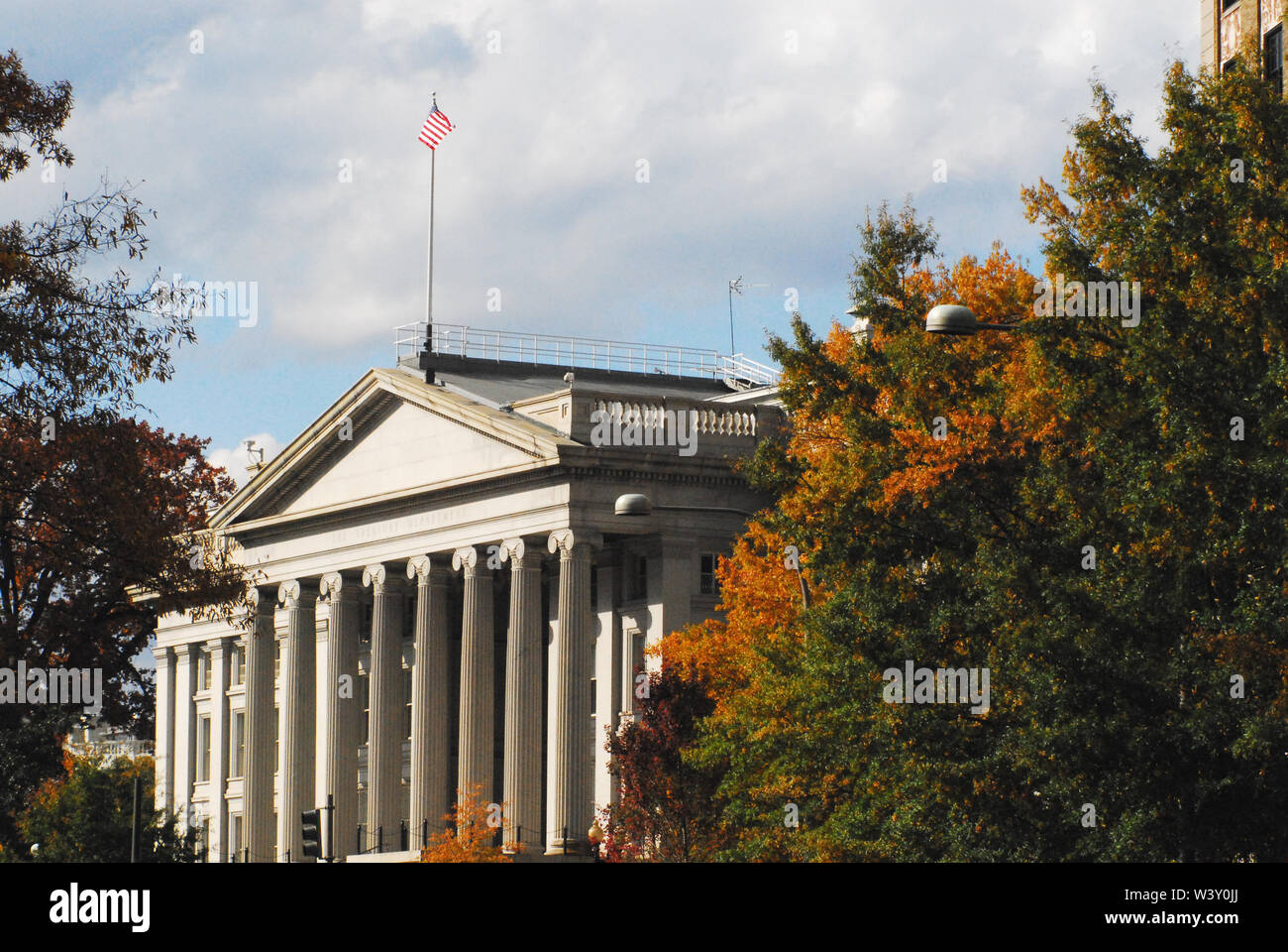 Neo-classical architecture of the Treasury Building surrounded by Autumn colors in Washington DC, USA. Note the US flag flying high. Stock Photo