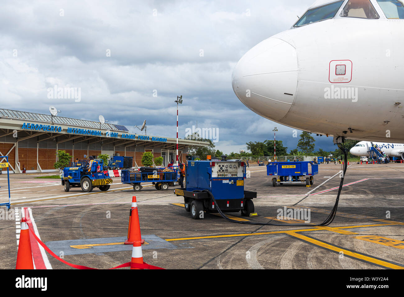 Ground crew servicing an Airbus A320 plane, outside the terminal building at Aeropuerto Internacional Padre Aldamiz, Puerto Maldonado,  Peru, South Am Stock Photo