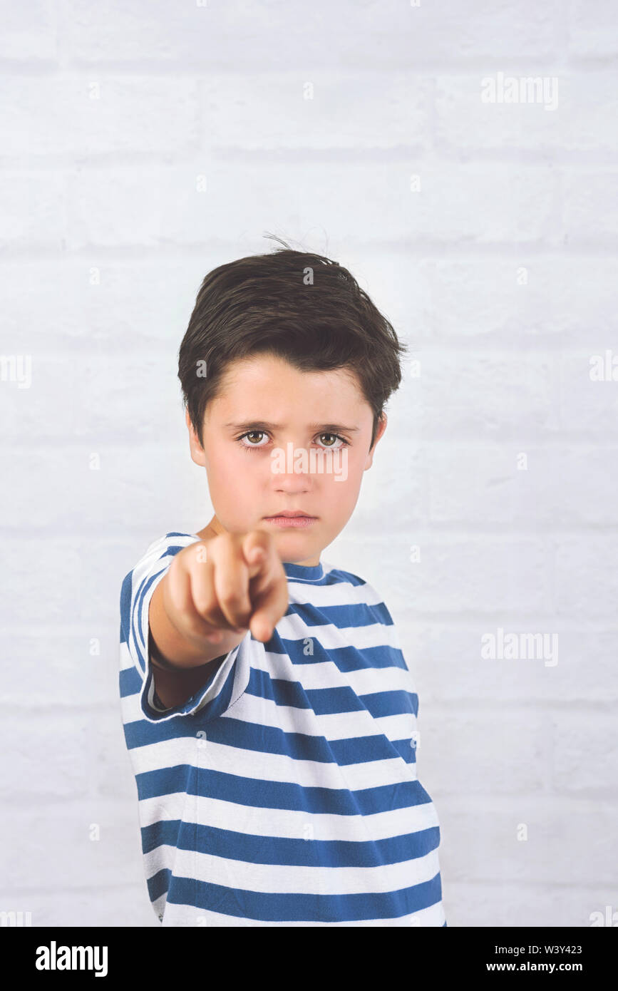 angry child pointing front against brick background Stock Photo