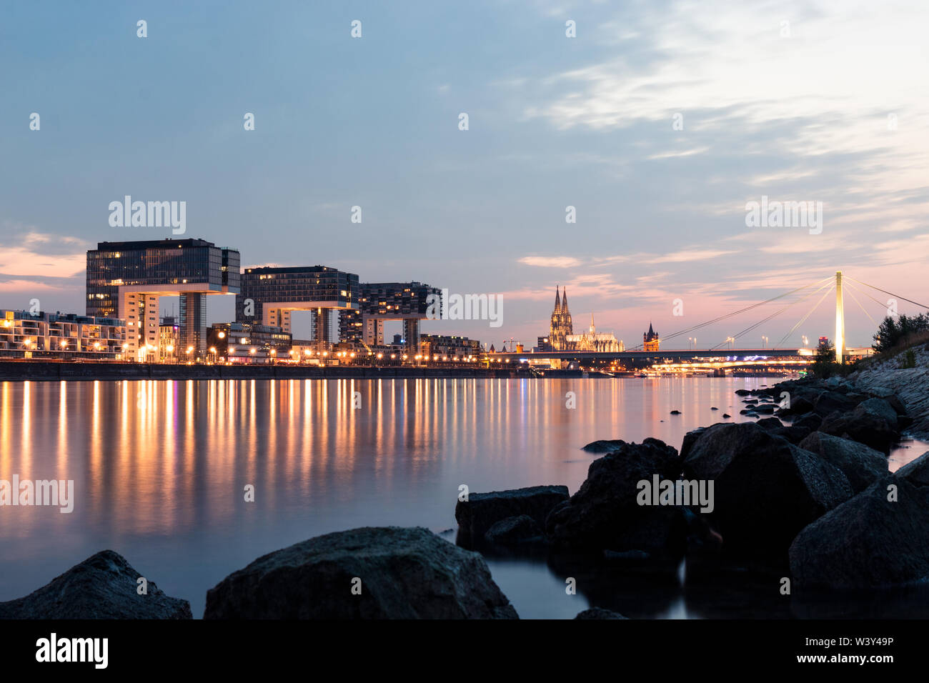 A wonderful long exposure in the evening, capturing the Rhine in the foreground and the crane houses with Cologne Cathedral in the background. Stock Photo