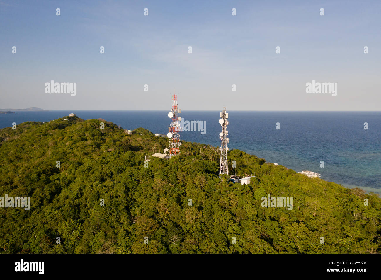 Telecommunication tower, communication antenna. Repeaters on a metal tower. Landscape with hills and rainforest, view from above. Tower with repeaters. Stock Photo