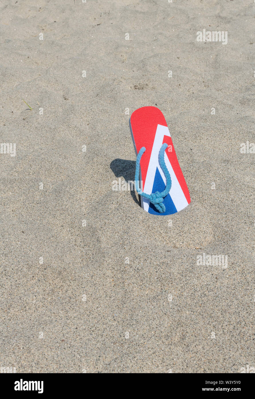 GB flag / Union Jack flip-flops on sandy beach - for 2021 UK staycation, holidays at home, staycation Cornwall, seaside holiday, flip-flop footwear. Stock Photo