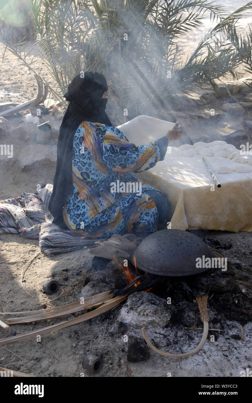 Bedouin woman baking bread outdoors Stock Photo