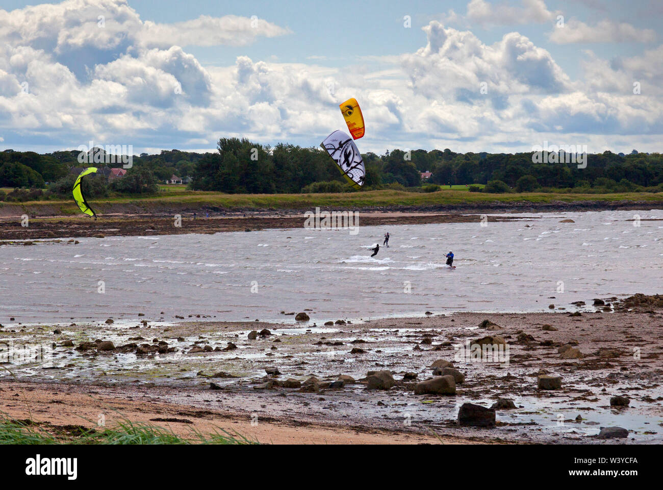 Longniddry Bents, East Lothian, Scotland. UK. 18th July 2019. Kitesurfers make the best of the sunny and windy but changeable conditions with 27km/h winds and potential gusts of 49 km/h, great skill was demonstrated as they passed close by each other without their kites becoming tangled up. Stock Photo