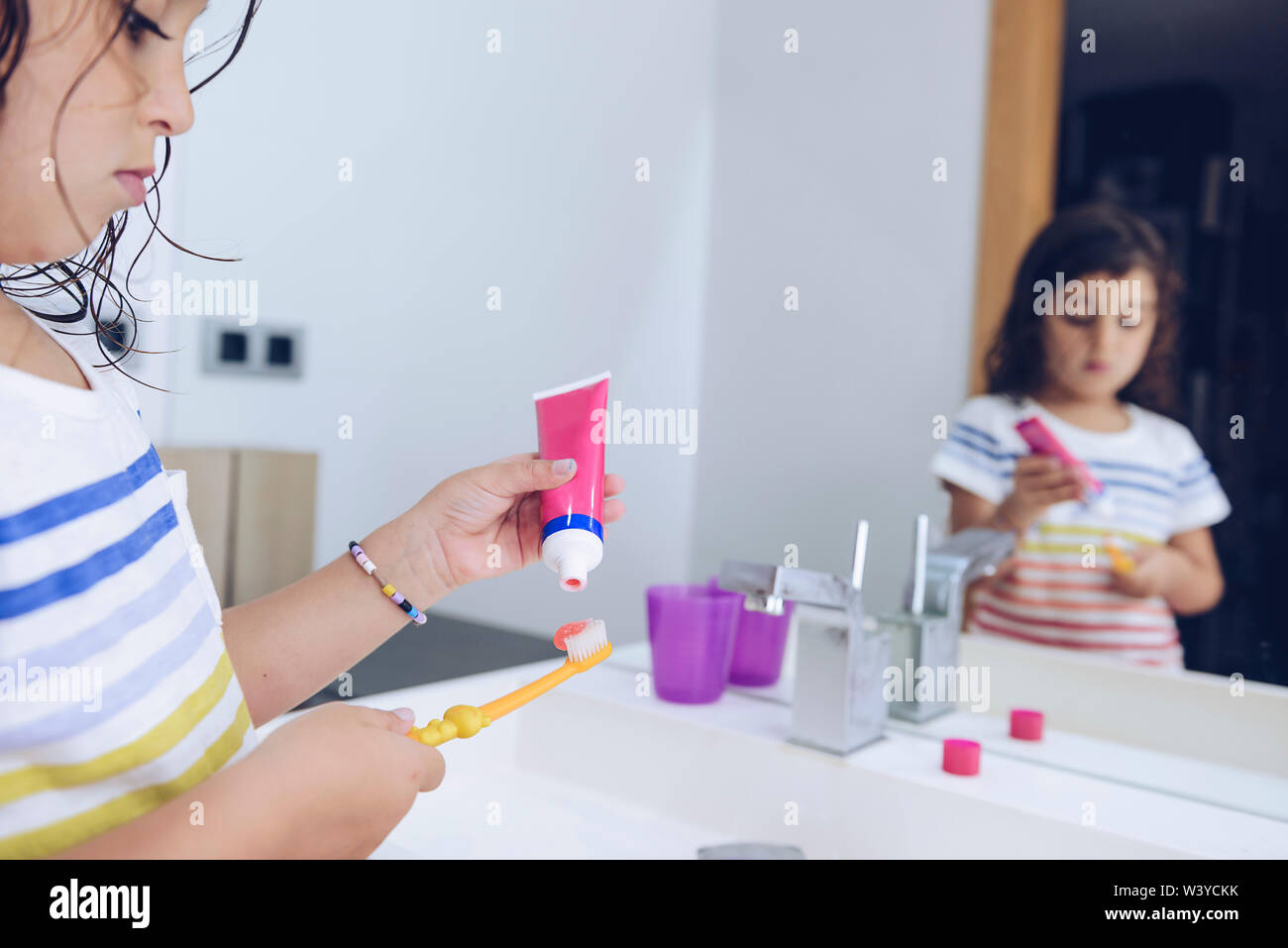 little girl putting toothpaste on the brush, after taking a shower she