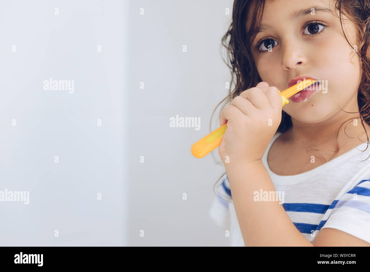 portrait of a little girl brushing her teeth in the bathroom in the