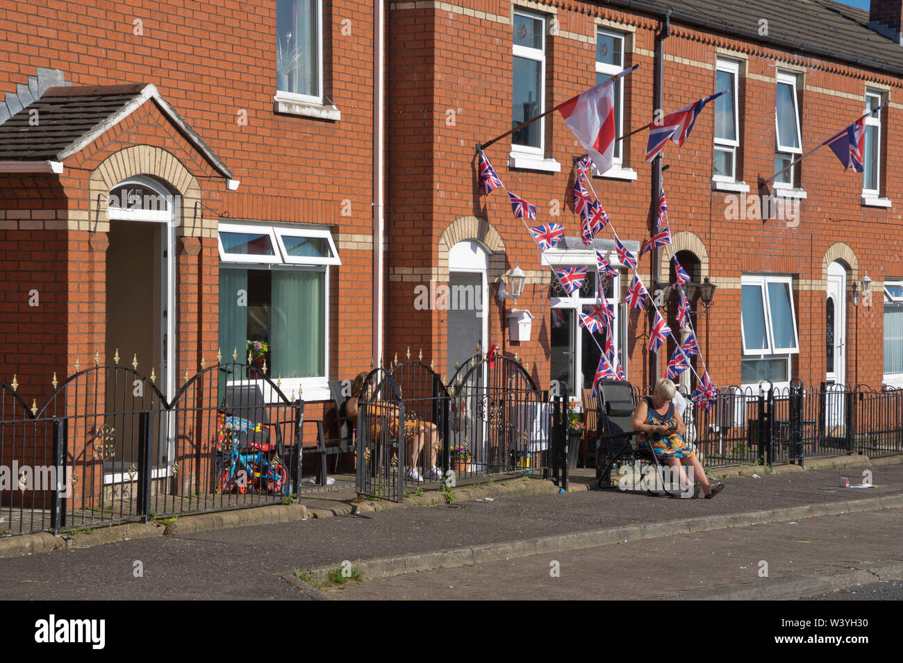 Family outside house with loyalist flags and banners in the Shankhill area of Belfast ,Northern Ireland Stock Photo