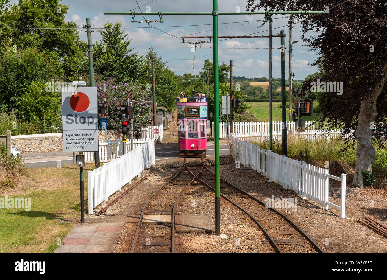 Seaton, Devon, England, UK. July 2019. Seaton Tramway. Electric tram.  Tramcar and passengers passing a level crossing Stock Photo