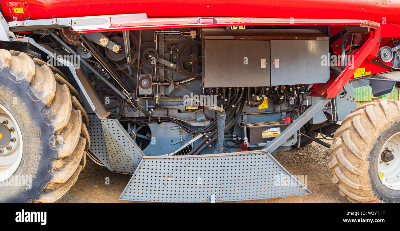 View under the guards of the left hand side of a Massey Ferguson 7278 combine harvester showing the drive belts and electrical cabinet Stock Photo