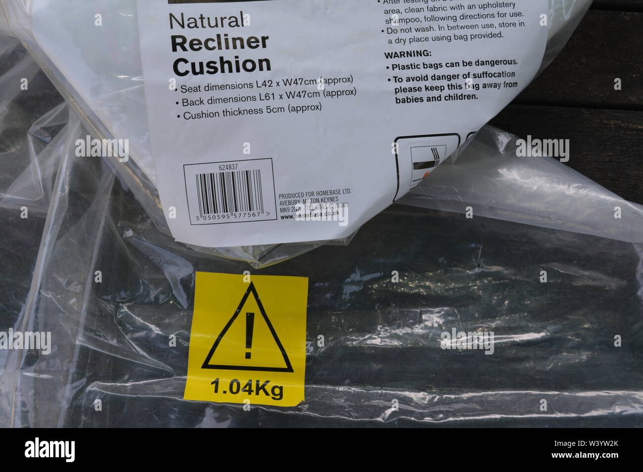 Yellow warning sticker showing weight of item on empty transparent plastic bag for garden seat cushion nanny state health and safety risk assessment Stock Photo