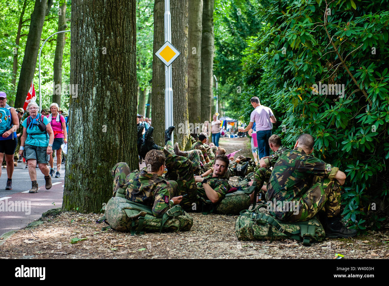 A group of soldiers rest during the third day.Since it is the world’s biggest multi-day walking event, the Four Days March is seen as the prime example of sportsmanship and international bonding between military servicemen and women and civilians from many different countries. The third day route is much known because of its seven hills, which are always a challenge to walkers. Some of the neighbourhoods of Nijmegen celebrate the arrival of the walkers by decorating the exteriors of houses and having great parties, which is always a very warm welcome to the participants. Stock Photo