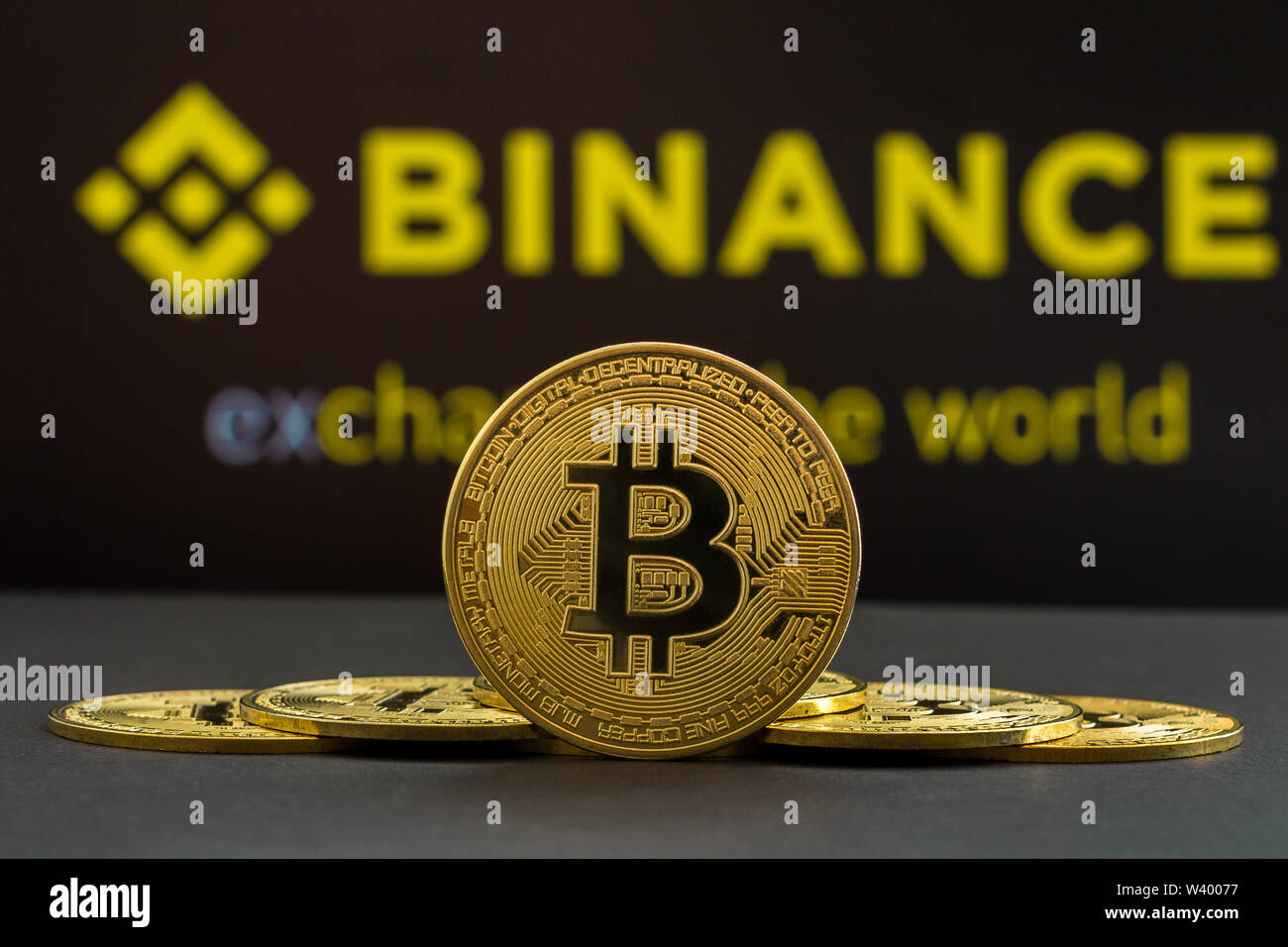 A big Bitcoin cryptocurrency coin in the centre and other bitcoin coins from both side in front of Binance crypto market . The pyramid of bitcoin Stock Photo