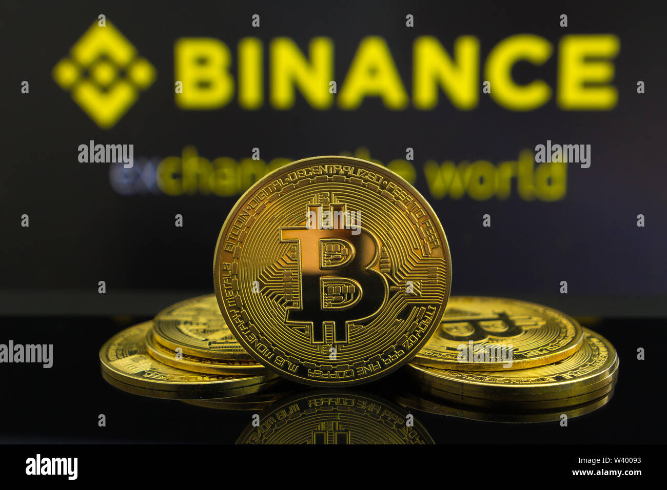 A big Bitcoin cryptocurrency coin in the centre and other bitcoin coins from both side in front of Binance crypto market . The pyramid of bitcoin Stock Photo