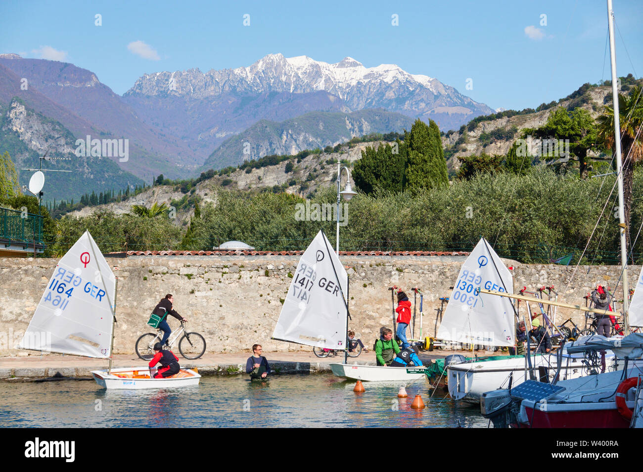Optimist sailing boats, motorboat, tourists at small harbor Porticciolo