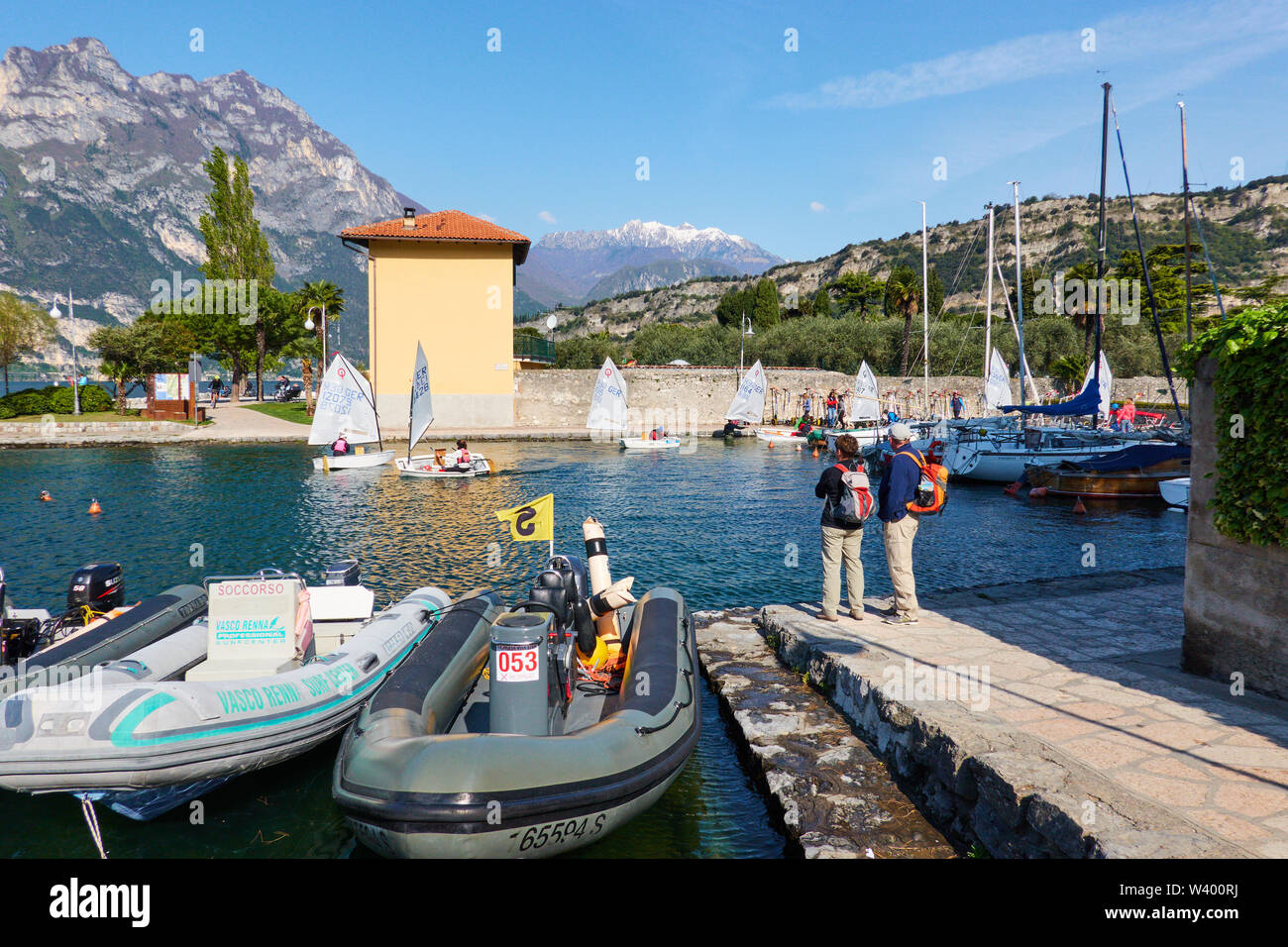 Optimist sailing boats, motorboat, tourists at small harbor Porticciolo