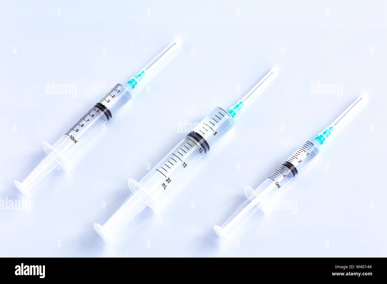 Three syringes of different capacity on a white table, prepared for injection in the hospital with copyspace for text.. Stock Photo