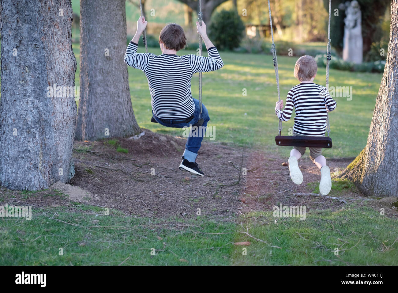 Man and boy ride on hanging swings Stock Photo Alamy