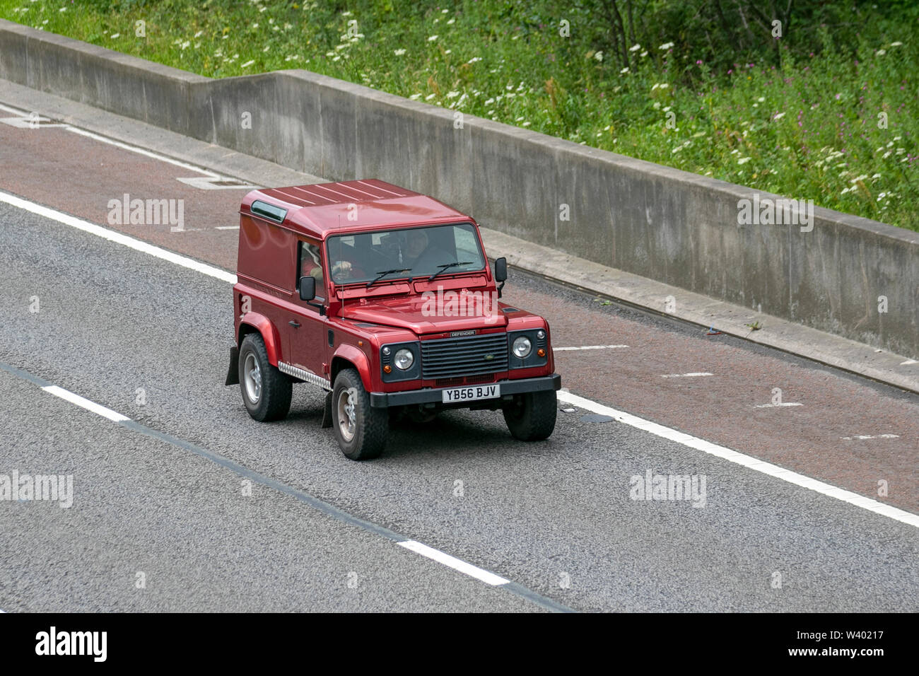 2007 red Land Rover Defender 90 County TD5; UK Vehicular traffic, transport, modern, saloon cars, south-bound on the 3 lane M6 motorway highway. Stock Photo