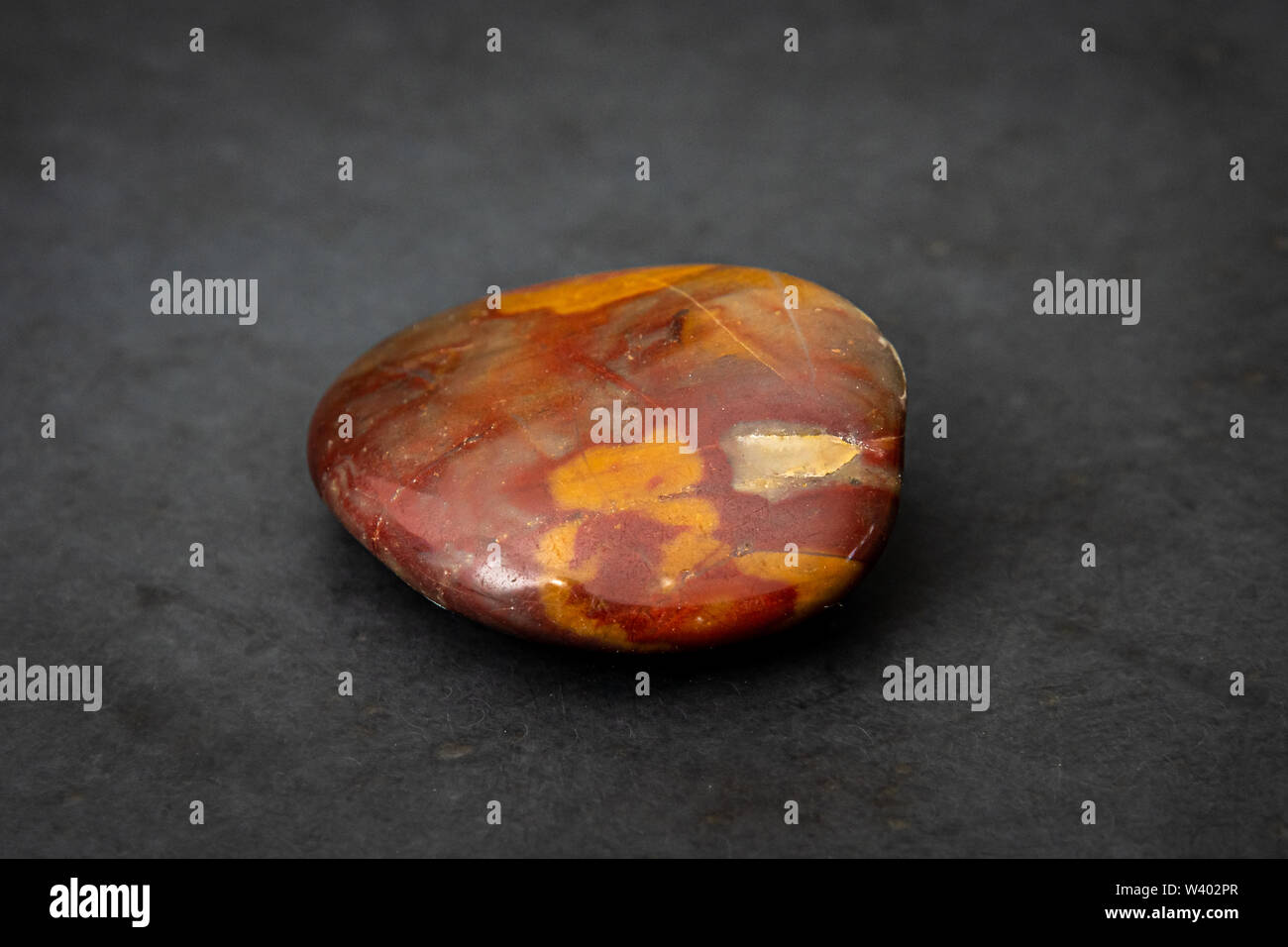 Red gemstone with colorful structure in many tones formed under high pressure found in river Stock Photo