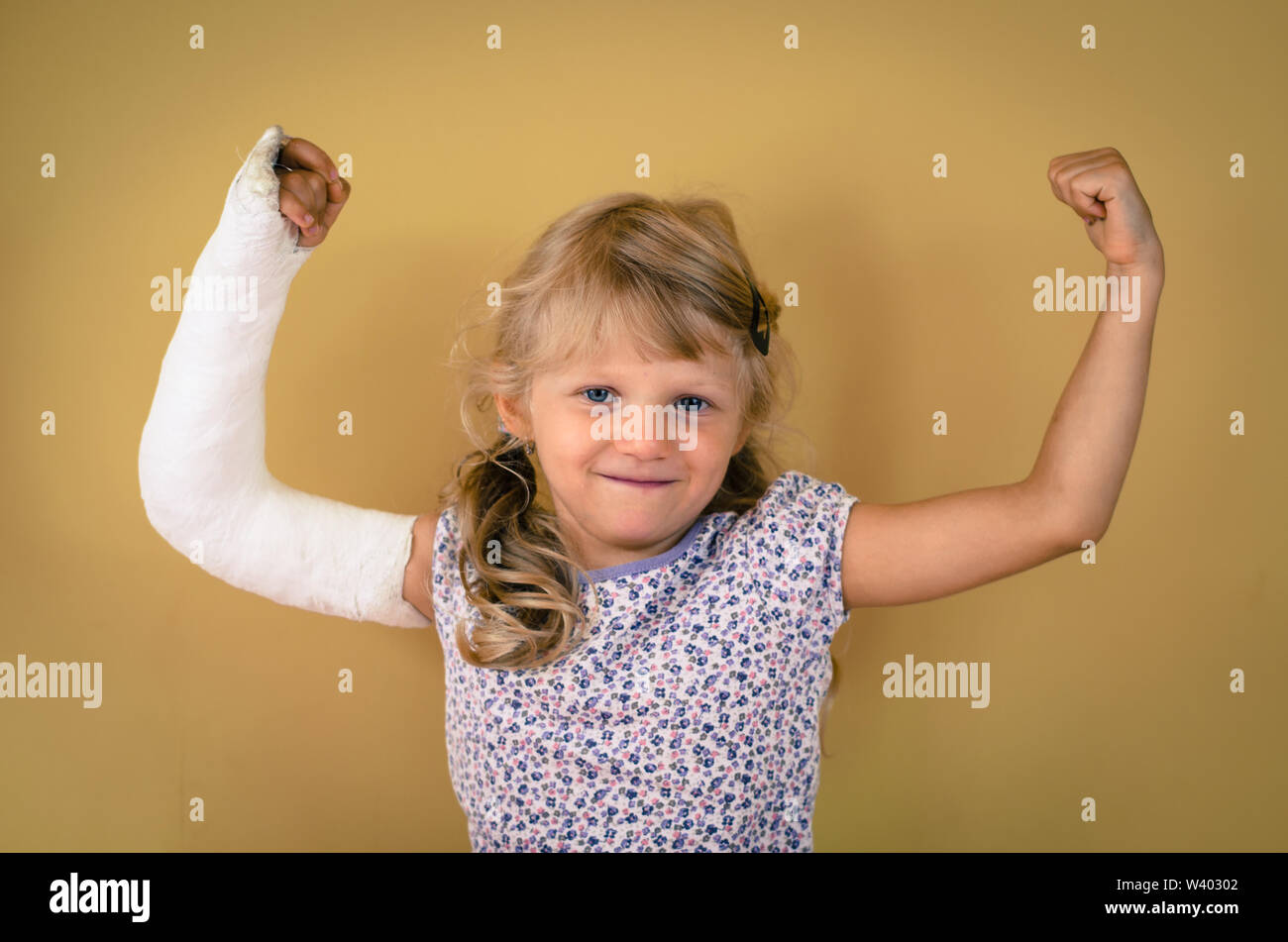 hurt blond girl with broken hand doing sport gesture of strength and triumph Stock Photo