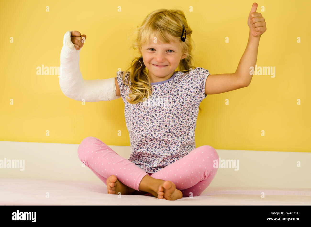 hurt blond girl with broken hand doing sport gesture of strength and triumph Stock Photo