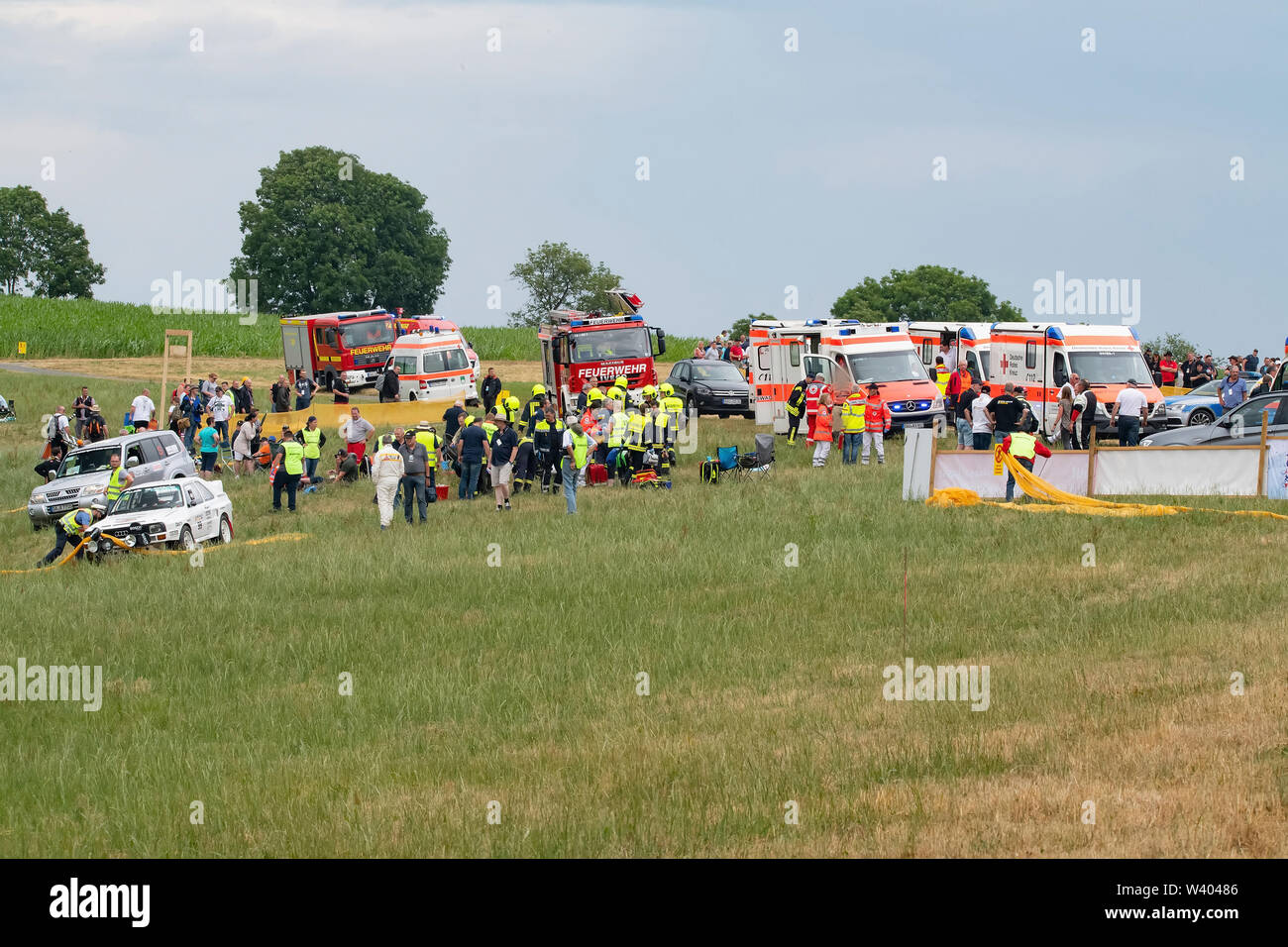 Daun, Germany. 18th July, 2019. Security guards help the injured at the scene of the accident. During a car rally in the Eifel several people were injured when a classic car coupe drove into a group of spectators. Credit: Jan Huebner/dpa/Alamy Live News Stock Photo