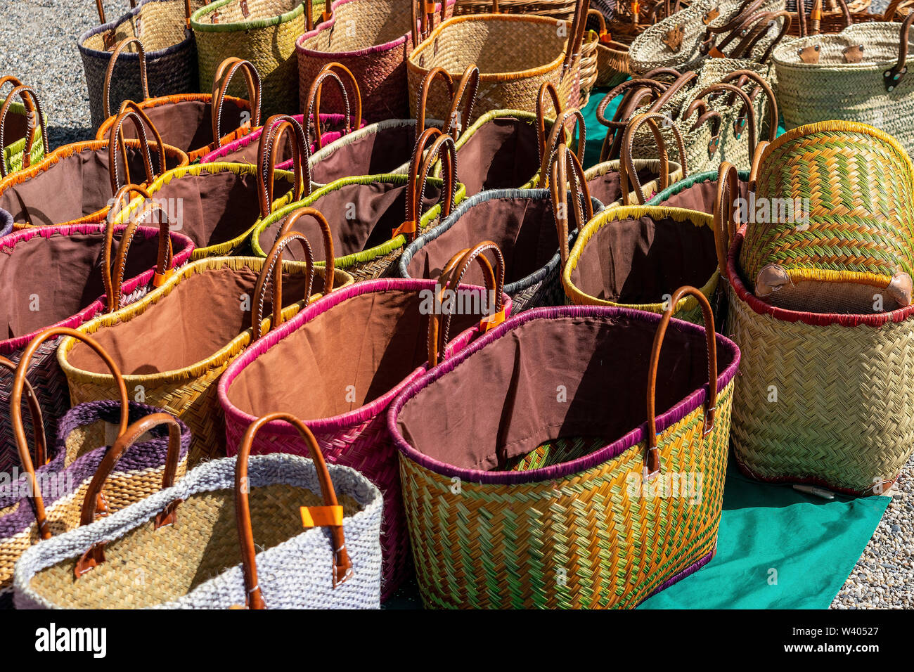 A display of colourful handmade wicker baskets for sale in a French market suitable for carrying shopping Stock Photo