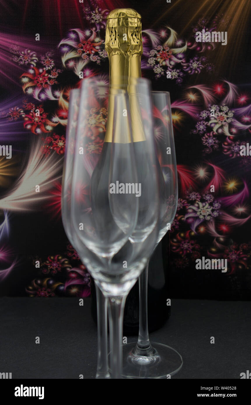 A bottle of champagne, champagne wine, behind champagne glasses. Dark background with abstract colorful flowers. Stock Photo