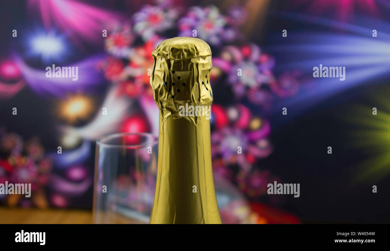 Top of champagne bottle, slightly back glass on sparkling wine, dark background with abstract flowers. Stock Photo