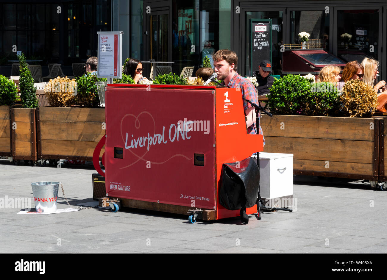 Young busker street musician singing at the piano in Liverpool One City Centre Stock Photo