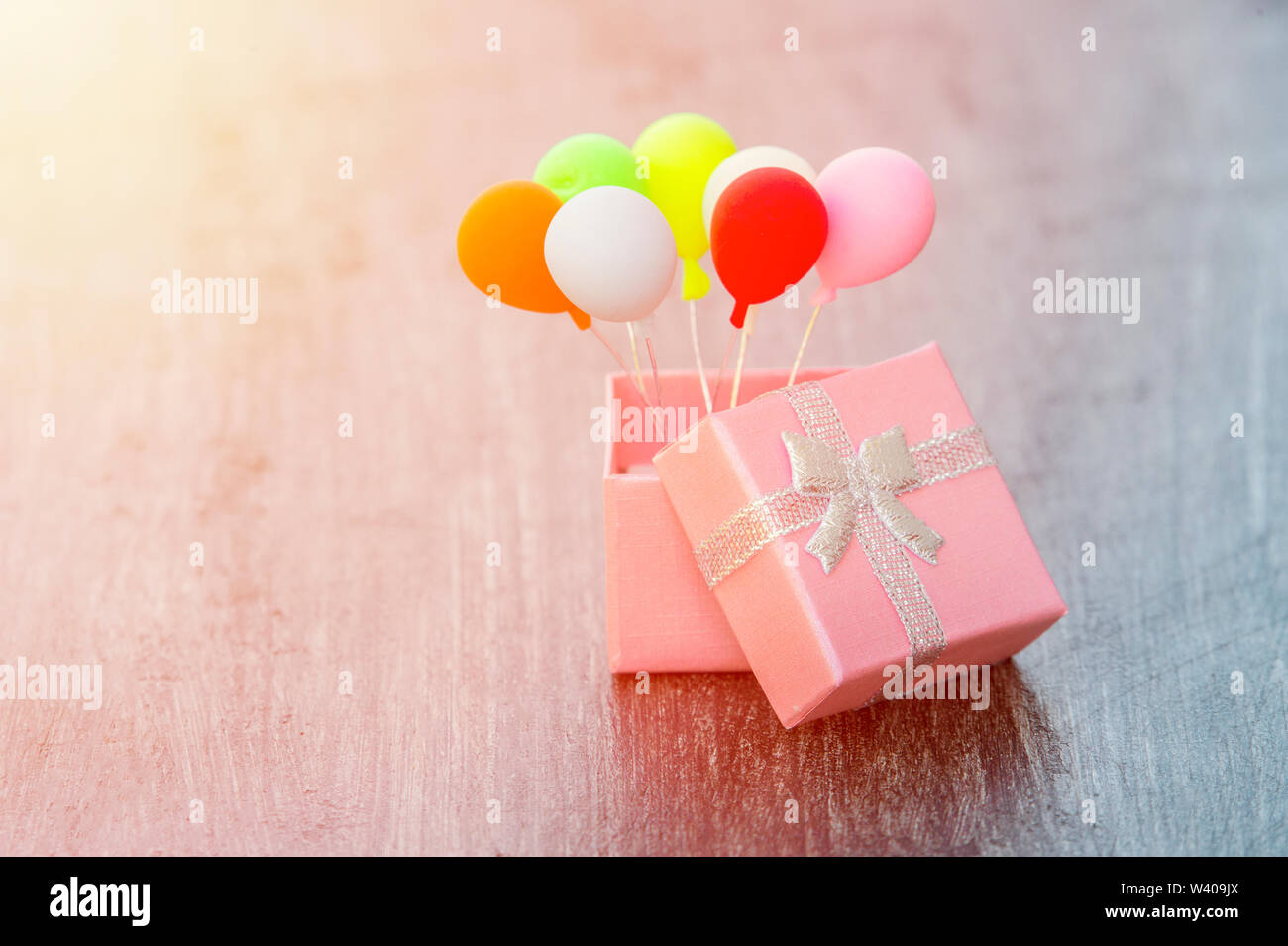 Pink gift box with silver ribbon and colorful balloon on wooden background. minimal hollyday concept Stock Photo