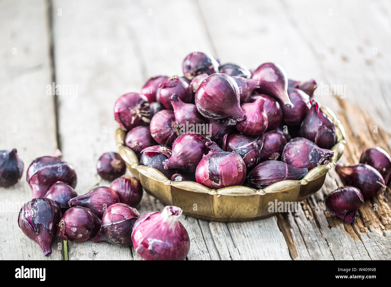 Red onion in bronze bowl on garden table. Close-up fresh healthy vegetable Stock Photo