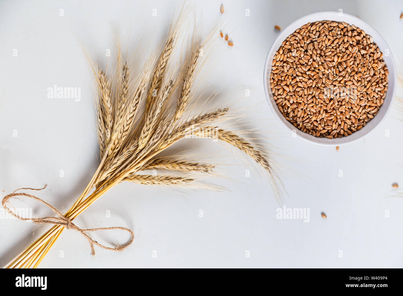 wheat ears and bowl of grains on white background, flat lay Stock Photo ...