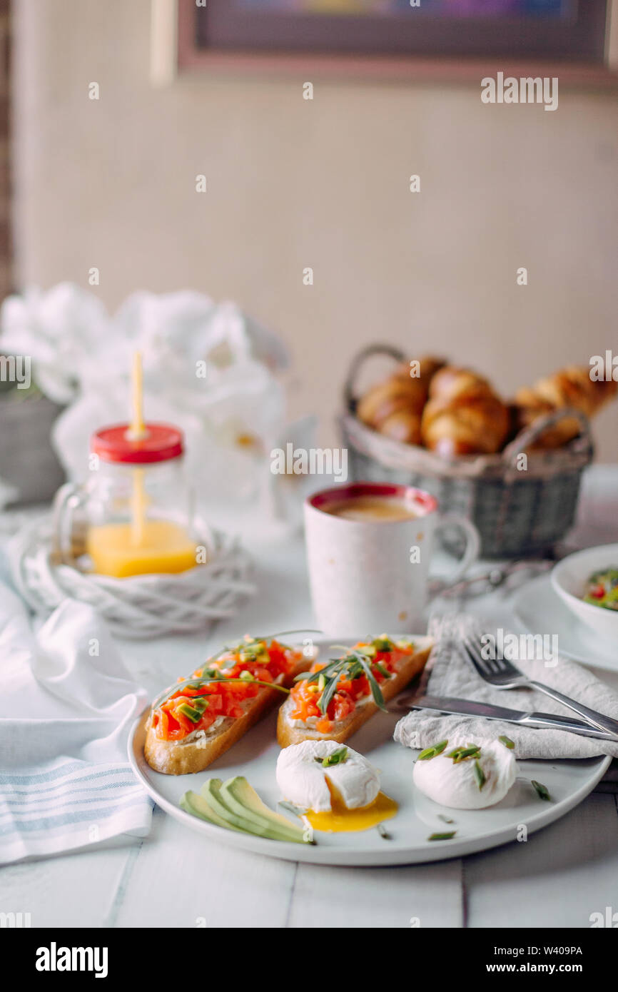 Photo of norway breakfast. Toasts with salmon and cream-cheese, boiled eggs  served om a white plate standing on a white wooden table with vegetable sa  Stock Photo - Alamy