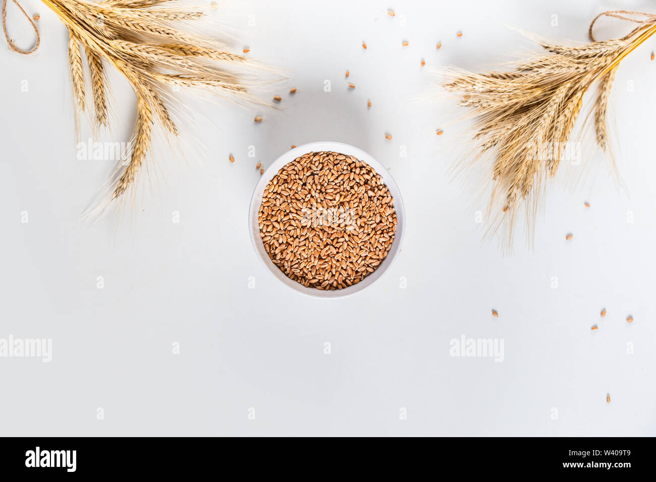 wheat ears and bowl of grains on white background, flat lay Stock Photo ...