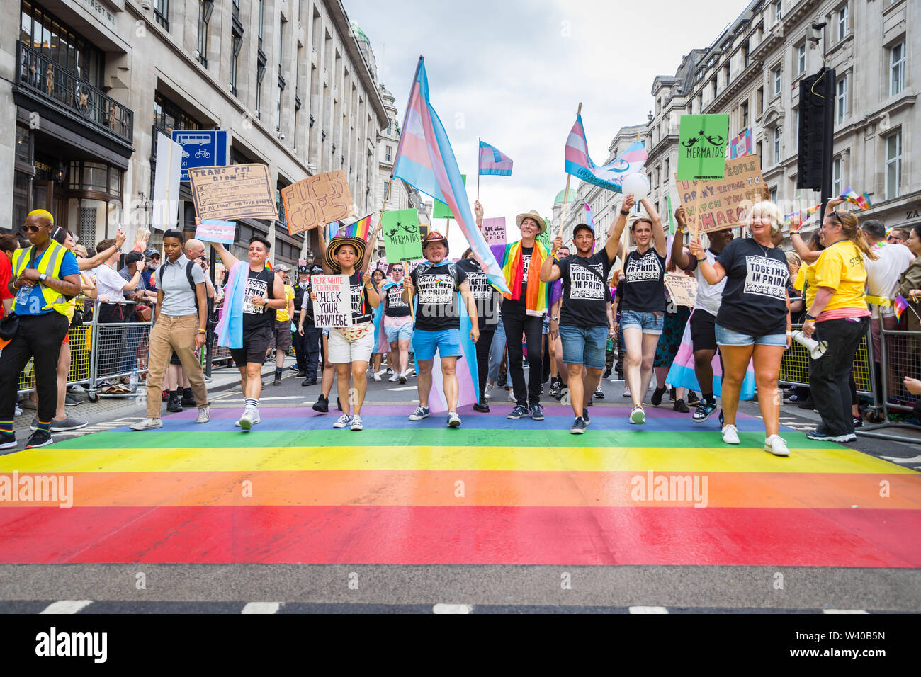 Marching group of Trans activists on the rainbow crossing at Pride Stock Photo