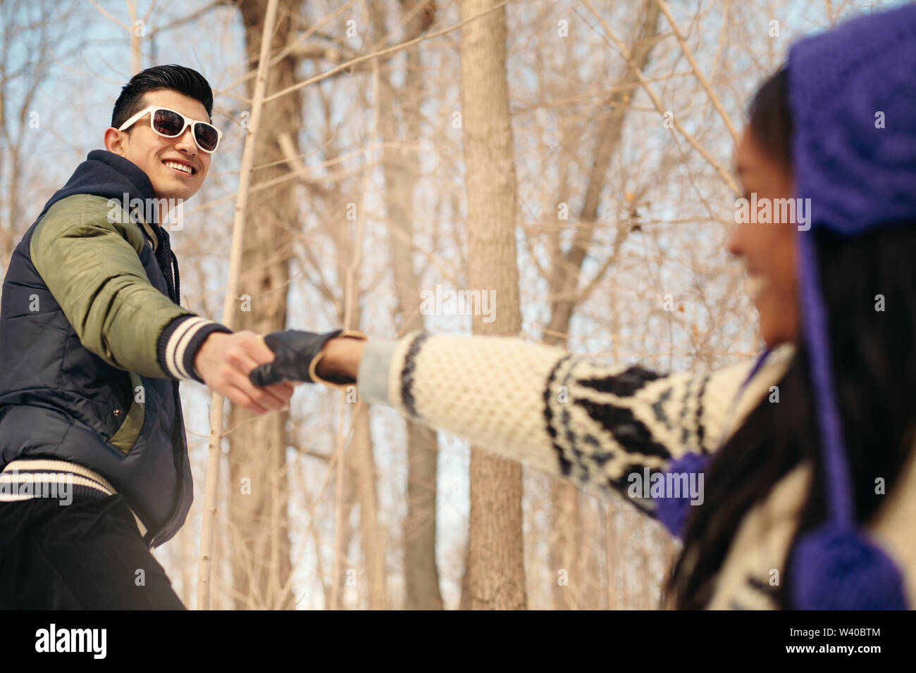 Couple reaching out while hiking in the snow in winter Stock Photo