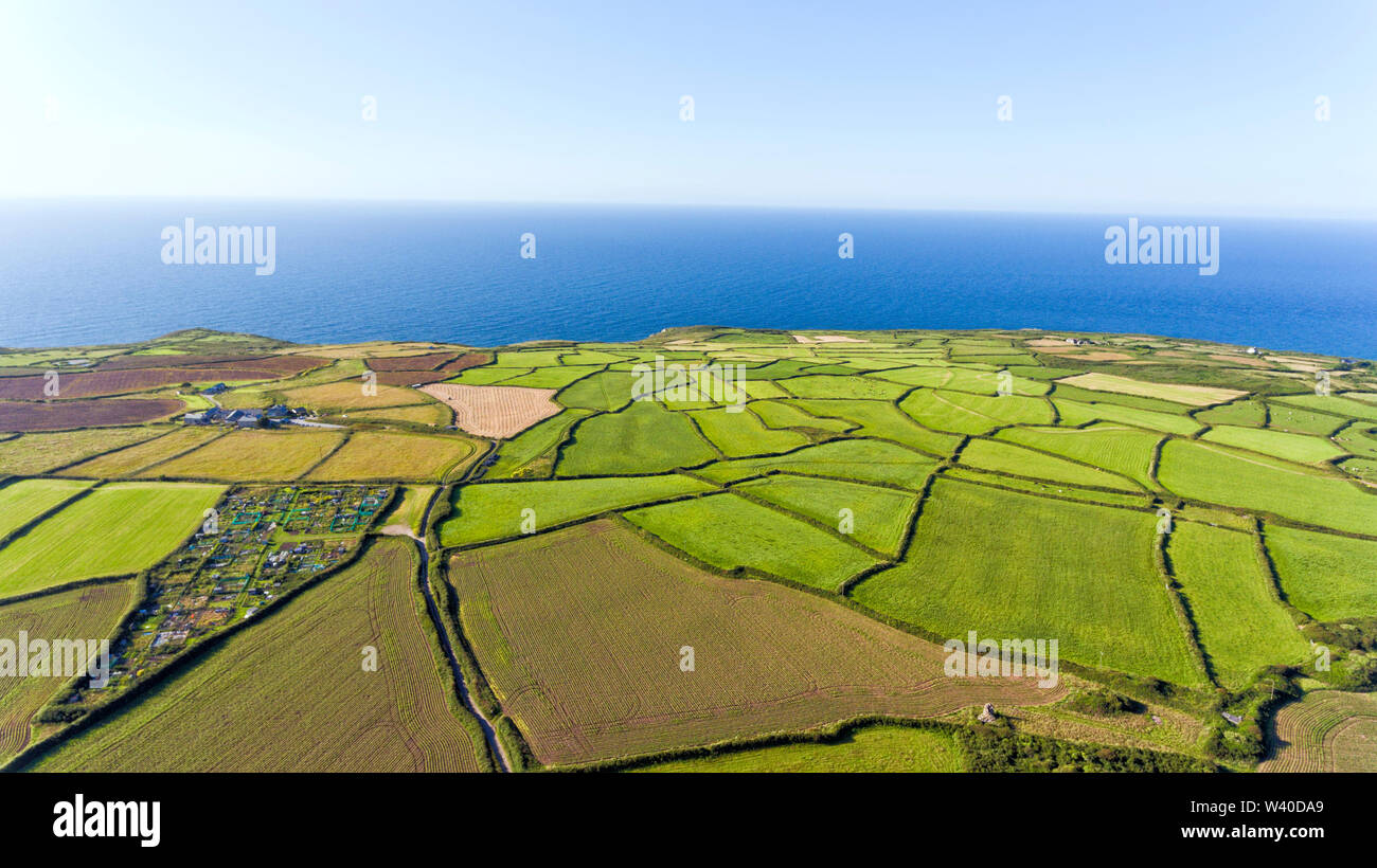 Aerial view of green, ploughed farm fields mosaic by Atlantic Ocean on the Cornish coast, on a summer clear day . Stock Photo