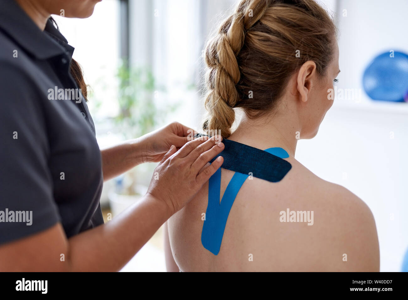 https://c8.alamy.com/comp/W40DD7/chinese-woman-massage-therapist-applying-kinesio-tape-to-the-shoulders-and-neck-of-an-attractive-blond-client-in-a-bright-medical-office-W40DD7.jpg