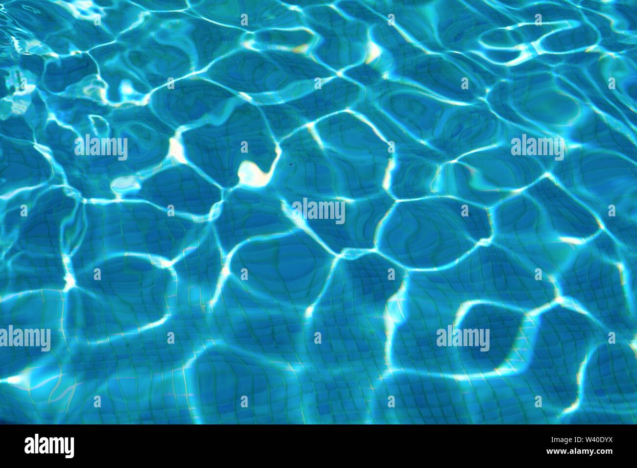 Abstract patterns formed by strong sunlight on the surface of water in a swimming pool  similar to  David Hockney's famous paintings Stock Photo