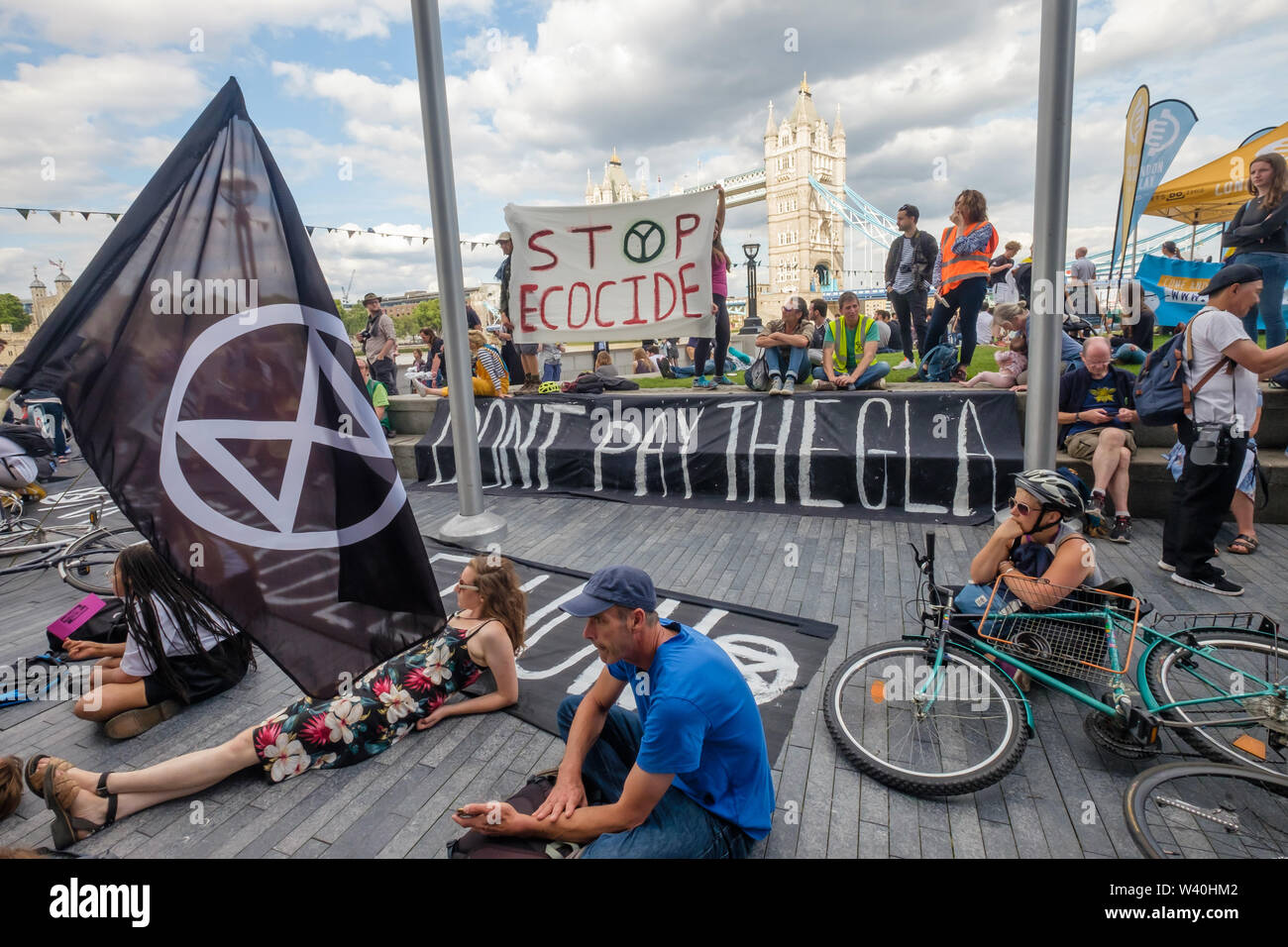 London, UK. 18th July 2019. Extinction Rebellion supporters at the City Hall rally and die-in to declare a tax strike against the Greater London Authority, withholding the GLA element of their council tax until they abandon projects which will cause environmental degradation and hasten ecological collapse. They demand the GLA stop all infrastructure projects polluting London’s air and invest in measures to cut carbon emissions and encourage healthier lifestyles and empower a citizen’s assembly to re-write the London Plan. Peter Marshall/Alamy Live News Stock Photo