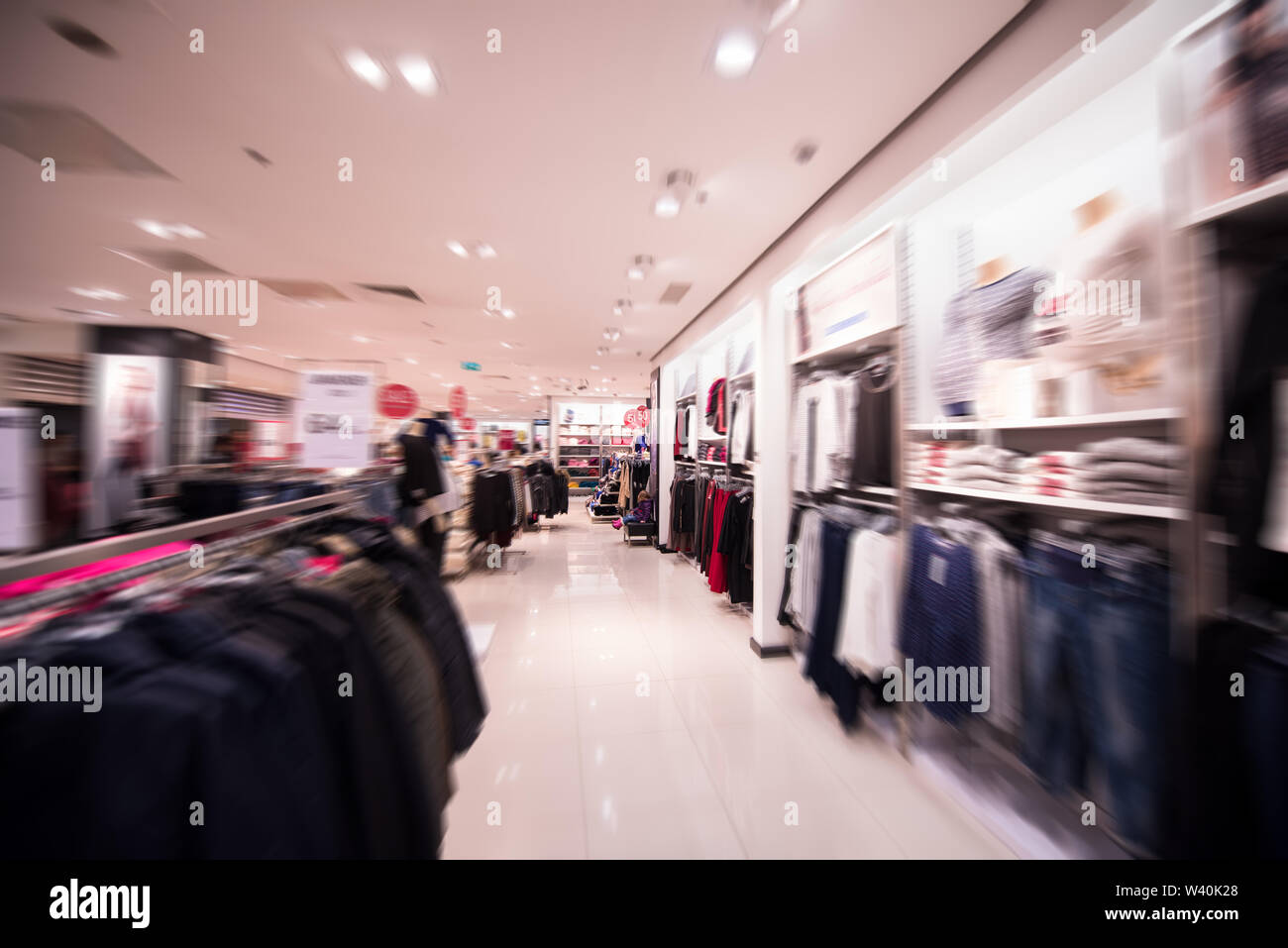 Little Cute Girl Sitting On The Bench In The Clothing Store Stock