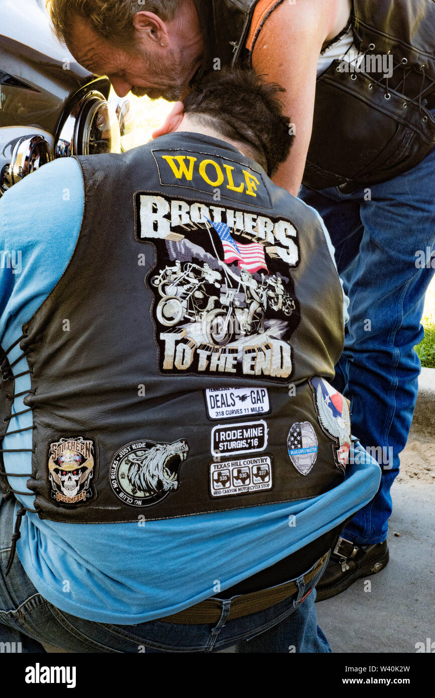 Biker, motorcycle rider, Harley-Davidson biker wearing leather vest with emblem patch working on motorcycle, Wolf Stock Photo