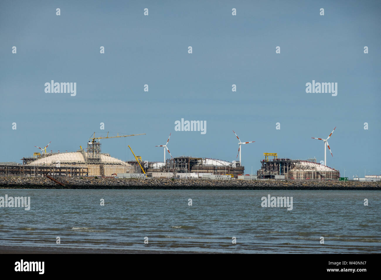Zeebrugge, Flanders, Belgium -  June 18, 2019: Closeup of LNG terminal in port of Zeebrugge under blue sky as seen from beach in Knokke-Heist. Stock Photo