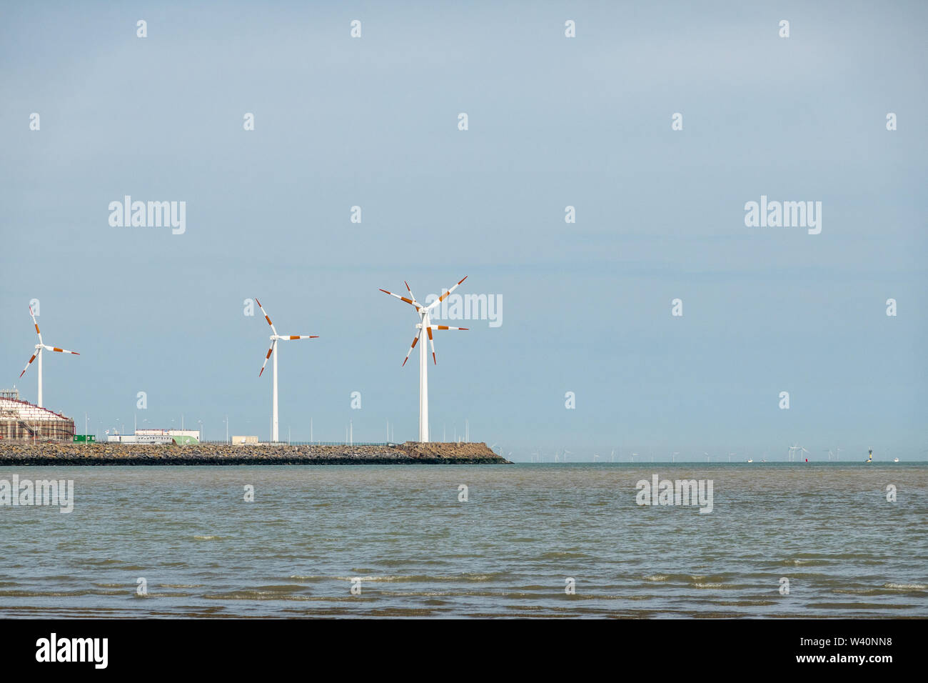 Knokke-Heist, Flanders, Belgium -  June 18, 2019: LNG terminal in port of Zeebrugge has windmils, but far on the horizon, barely visible, are more of Stock Photo