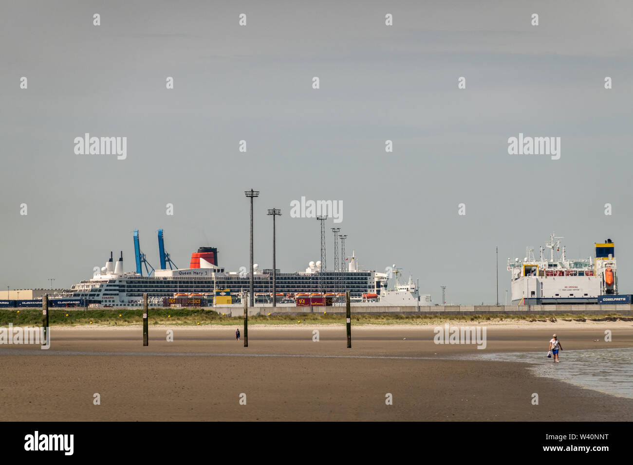 Zeebrugge, Flanders, Belgium -  June 18, 2019: Queen Mary 2 Cruise Ship in port of Zeebrugg as seen from beach in Knokke-Heist under gray-blue sky. We Stock Photo